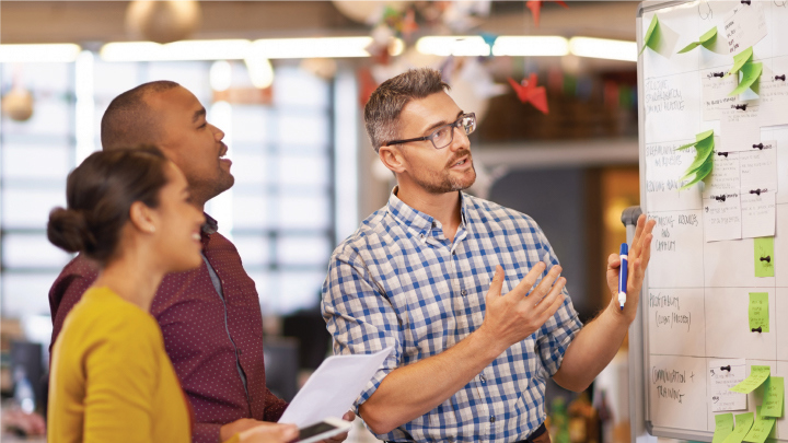 Group of people looking at a project board.