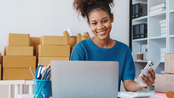 Person working on a laptop with shipping boxes behind them.